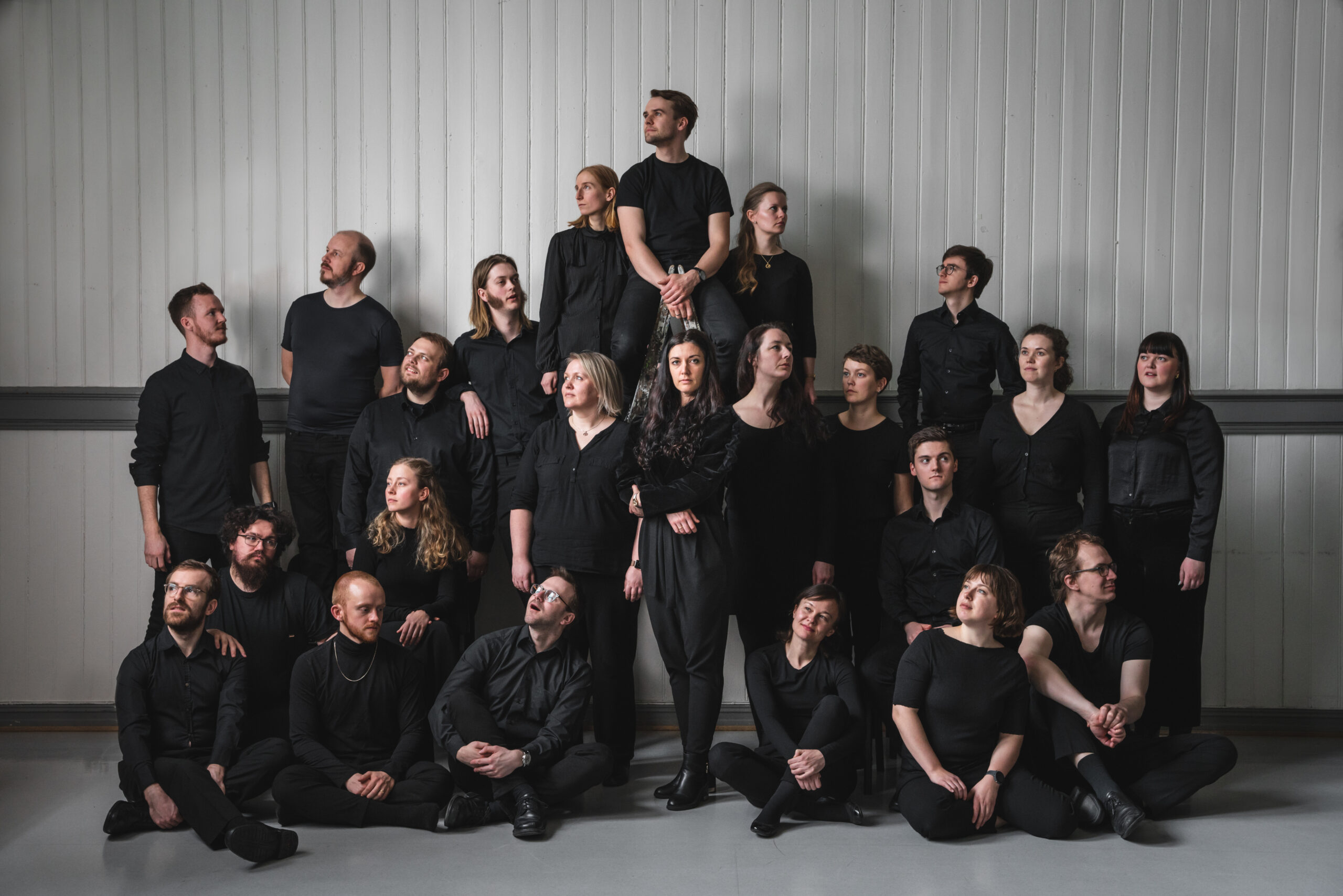 Kammerkoret Aurum ser i alle retninger mens dirigent Eva Holm Foosnæs i midten ser inn i kamera. Foto: Kasper Eliassen